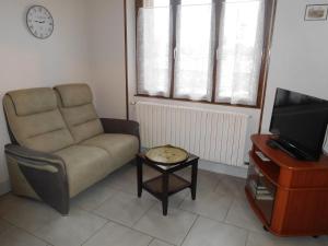 ein Wohnzimmer mit einer Couch, einem Fernseher und einem Tisch in der Unterkunft Les pivoines in Richebourg
