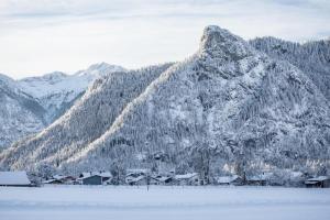 a snow covered mountain with a town in front of a lake at Ammerglück Apartments in Oberammergau