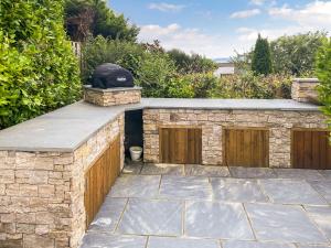 Un patio de piedra con barra con parrilla. en Shearwaters, en Saint Mawes