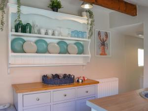 a kitchen with white cabinets and blue dishes on shelves at Peace Cottage in Flamborough