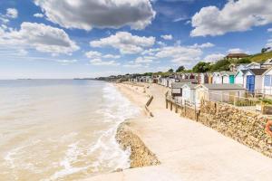 einen Strand mit einer Reihe von Häusern und dem Meer in der Unterkunft Spacious 8 Berth Caravan With Decking At Naze Marine In Essex Ref 17012Rd in Walton-on-the-Naze