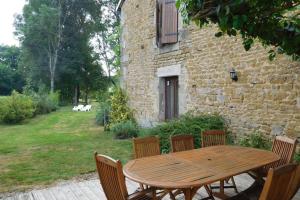 een houten tafel en stoelen voor een gebouw bij Les jardins de recourt in Récourt