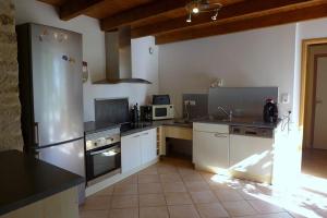 een keuken met een roestvrijstalen koelkast en witte kasten bij Les jardins de recourt in Récourt