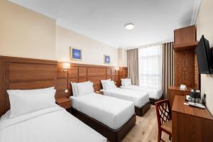 a hotel room with three beds and a desk at Kingsgate Hotel Deyar in Medina