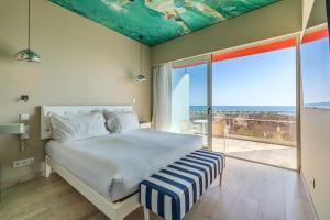 Pestana Alvor South Beach Premium Suite Hotel في ألفور: غرفة نوم بها سرير ونافذة كبيرة +51 صورة