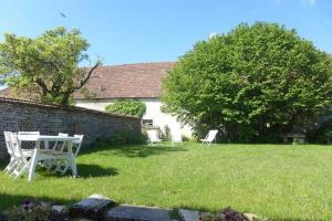 2 weiße Stühle und ein Tisch im Hof in der Unterkunft La maison de gabrielle in Giey-sur-Aujon