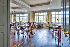 a dining room with tables and chairs and windows at George of Piercebridge in Piercebridge