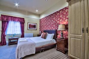 a bedroom with a bed and red wallpaper at George of Piercebridge in Piercebridge