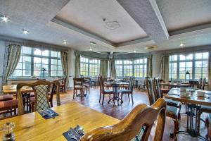 a restaurant with wooden tables and chairs and windows at George of Piercebridge in Piercebridge