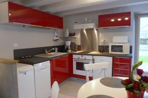 een keuken met rode kasten, een tafel en een magnetron bij La p'tite cuisine in Faverolles +5 foto's