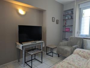 een woonkamer met een flatscreen-tv en een stoel bij Gite simone de beauvoir in Châteauvillain