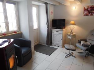 een woonkamer met een bank en een televisie bij La p'tite cuisine in Faverolles