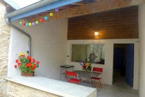 een patio met een tafel en stoelen en een tafel met bloemen bij Gite simone de beauvoir in Châteauvillain +5 foto's