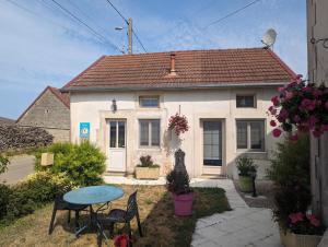 een klein huis met een tafel en stoelen ervoor bij La p'tite cuisine in Faverolles