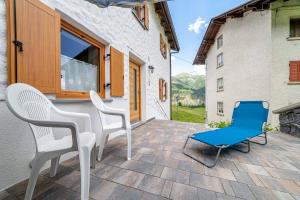 patio z 2 krzesłami i niebieskim krzesłem w obiekcie Ospitalità Diffusa Laste Dolomites Cèsa del Bèrba Jaco w mieście Colle Santa Lucia