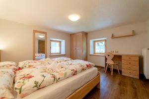 sypialnia z dużym łóżkiem i biurkiem w obiekcie Ospitalità Diffusa Laste Dolomites Cèsa del Bèrba Jaco w mieście Colle Santa Lucia