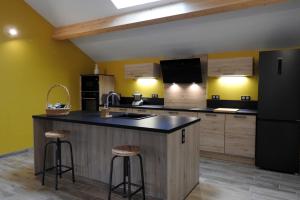 una cucina con pareti gialle e frigorifero nero di L'etape du general a Colombey-les-deux-Églises
