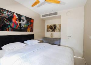 a bedroom with a bed with a large painting on the wall at Amazing 2Bdrm penthouse in JLM with balcony and view - פנטהאוז ירושלים in Jerusalem