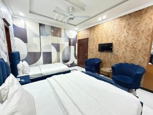 a room with a bed and chairs and a tv at Sky Lodge Guest House in Islamabad
