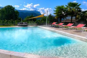 a large swimming pool with red chairs and a table at Hotel Garni Grüner Baum (Albero Verde) in Laives