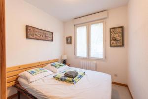 ein kleines Schlafzimmer mit einem weißen Bett und einem Fenster in der Unterkunft T2 Bis - centre Barèges - cure in Barèges