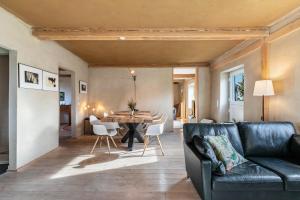 ein Wohnzimmer mit einer schwarzen Couch und einem Tisch in der Unterkunft Lehmhuus in Klanxbüll