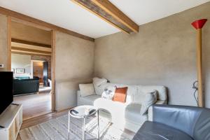 ein Wohnzimmer mit einem weißen Sofa und einem Fernseher in der Unterkunft Lehmhuus in Klanxbüll