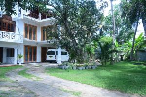 a white house with a tree in the yard at A&A Homestay in Seeduwa