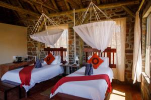 two beds in a room with wooden ceilings at Tsauchab River Camp in Sesriem