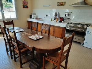 een keuken met een houten tafel met stoelen en een fornuis bij Gite de la forge in Bettaincourt-sur-Rognon