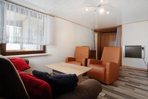un salon avec un canapé, des chaises et une télévision dans l'établissement Ferienhaus Am Darß - Kogge, à Pruchten