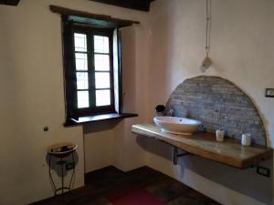 Ca' Rionda - Antica Casa Rurale في Osiglia: حمام مع حوض ونافذة