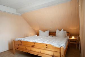 un lit avec des draps blancs et des oreillers dans une chambre dans l'établissement Ferienhaus Am Darß - Kogge, à Pruchten