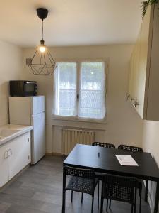 een keuken met een tafel, stoelen en een koelkast bij Grand Studio avec loggia in Thorigny-sur-Marne