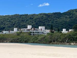 a building on the shore of a beach with trees at Flat 3 suites frente mar in Florianópolis