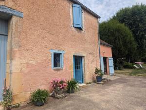 een bakstenen gebouw met een blauwe deur en bloemen bij Le nancery in Langres