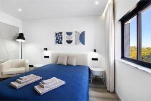 ein weißes Schlafzimmer mit einem blauen Bett und einem Fenster in der Unterkunft Casa das Amendoeiras in Pechão