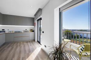 eine Küche mit weißen Schränken und einem großen Fenster in der Unterkunft Casa das Amendoeiras in Pechão