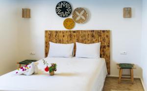 a bedroom with a white bed with a wooden headboard at Igiwano guest house in Essaouira
