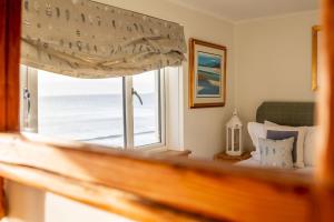 a bedroom with a view of the ocean from a window at Rockhopper Cottage Lower Largo in Lower Largo