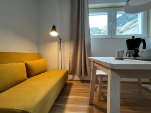 Una sala de estar con un sofá amarillo y una mesa. en Ferienwohnung Bergufer - Studio im Souterrain, en Oberammergau