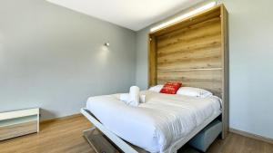 um quarto com uma cama com lençóis brancos e almofadas vermelhas em El Refugio Sujadaro em Osséja