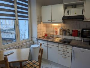 a kitchen with white cabinets and a table and a sink at Largo in Bourbonne-les-Bains