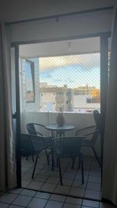 a table and chairs in a room with a window at Apartamentocamboinhapraiapiscinaeconforto in Cabedelo