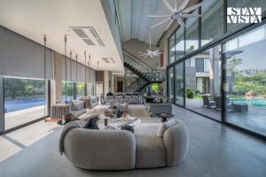 a large living room with couches and a pool at StayVista at Acasa with Lawn in Alibaug +32 photos