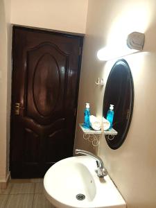 a bathroom with a sink and a brown door at Rukeja-PKK Homestays Nanyuki Town in Nanyuki