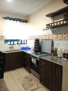 a kitchen with a stove and a sink at Rukeja-PKK Homestays Nanyuki Town in Nanyuki
