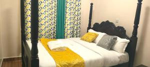 a bed with a black frame and pillows on it at Rukeja-PKK Homestays Nanyuki Town in Nanyuki