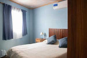 una camera da letto con un letto con pareti blu e una finestra di Taruca Apart a Ciudad Evita