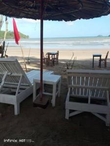 two chairs and an umbrella on a beach at Akoya Beachpark and Cottages in El Nido